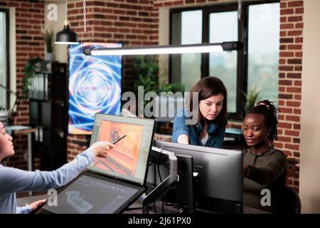 3D graphics designers in creative agency office workspace developing video game project. Company diverse employees discussing about development progress and electronic arts. Stock Photo