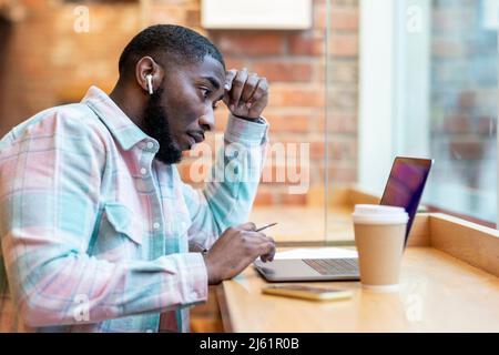 Freelancer using laptop sitting at cafe Stock Photo