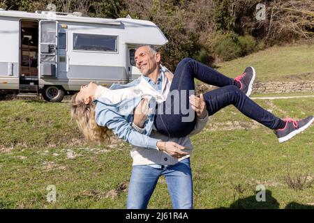 Man carrying woman standing in front of camper van Stock Photo