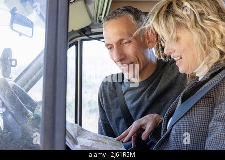 Mature couple looking at map and talking inside camper van on weekend travel Stock Photo