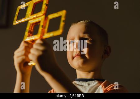 Boy holding yellow magnetic tiles in hand Stock Photo