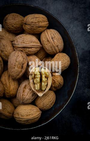 Studio shot of bowl of walnuts lying against black background Stock Photo