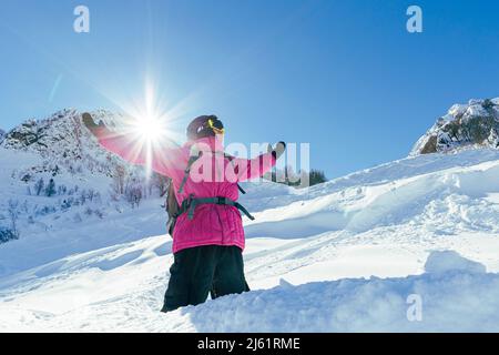 Man standing with arms outstretched at snowy mountain on sunny day Stock Photo