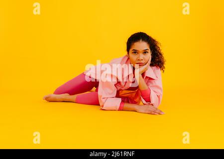 Young woman with head in hand leaning against yellow background Stock Photo