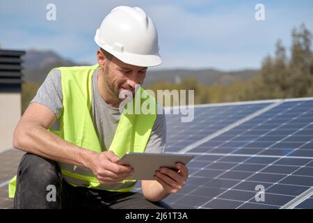 Smiling engineer using tablet PC by solar panels on sunny day Stock Photo