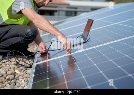 Engineer plugging in laptop power supply cable charger to solar panels Stock Photo