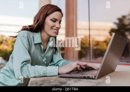 Happy freelancer using laptop outdoors Stock Photo