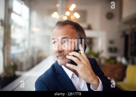 Senior businessman talking on mobile phone in cafe Stock Photo