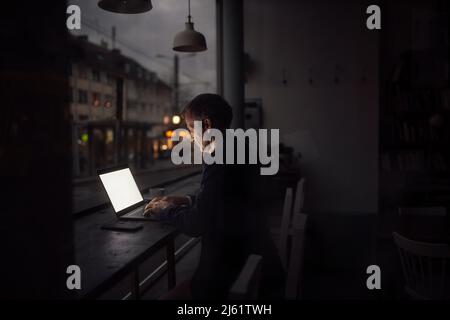 Businessman working on laptop in dark at cafe Stock Photo