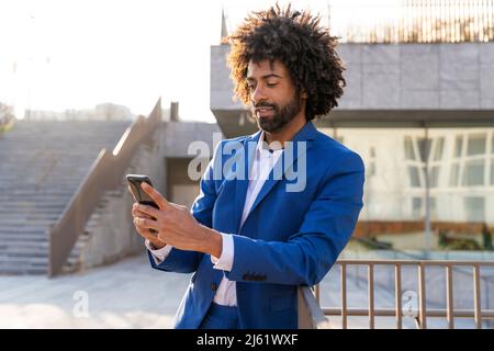 Businessman using mobile phone leaning on railing Stock Photo