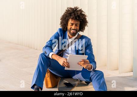 Smiling businessman with mobile phone using tablet PC sitting on skateboard Stock Photo