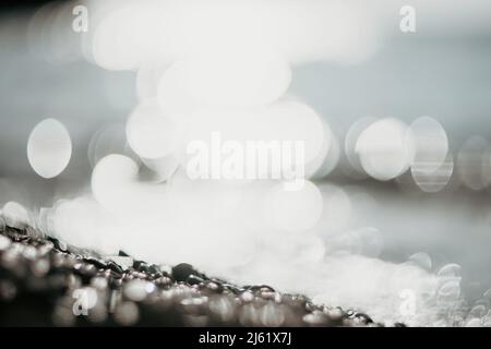 Abstract nature summer ocean sunset sea background. Small waves on water surface in motion blur with bokeh lights from sunrise. Holiday, vacation and Stock Photo