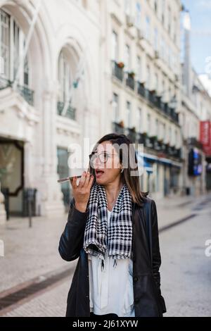 Woman sending voicemail through mobile phone in city Stock Photo