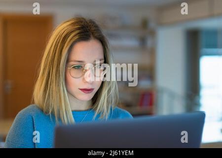 Young blond woman using laptop sitting at table Stock Photo