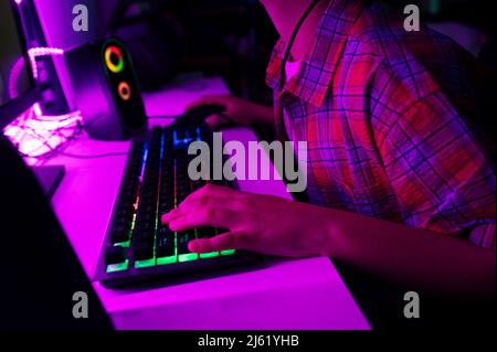 Boy with computer keyboard playing game sitting at table Stock Photo