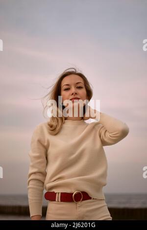 Beautiful woman standing in front of sky at sunset Stock Photo