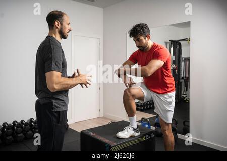 Instructor guiding young man at health club Stock Photo