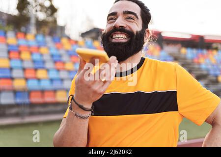 Happy bearded man talking on smart phone through speaker Stock Photo