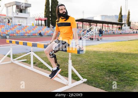 Man with prosthetic leg sitting on hurdle Stock Photo