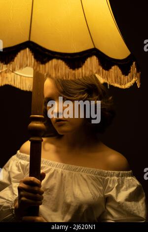 Young woman standing under illuminated lamp Stock Photo