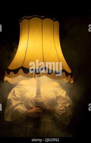 Young woman holding smoky illuminated lamp in front of face Stock Photo