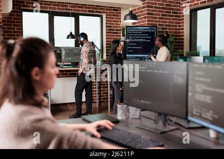 Team developing additional layers of security in order to sustain good functionality of system. Mixed race back end network developers analyzing interface database cloud processing method. Stock Photo