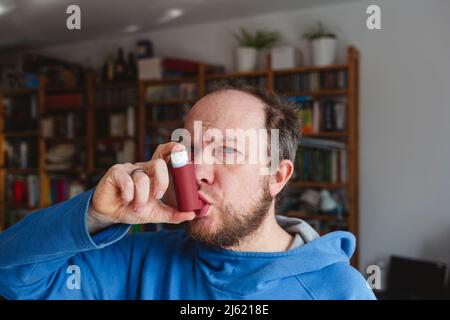 Man using asthma inhaler at home Stock Photo