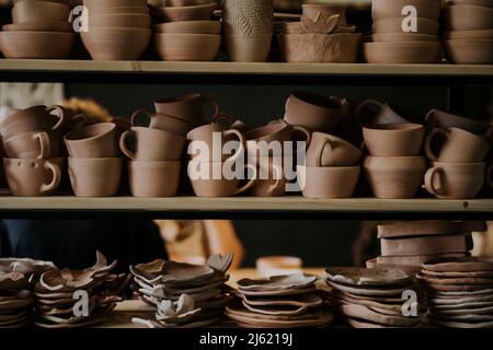 Handmade ceramic bowls with cups and plates on shelf in workshop Stock Photo