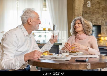 Senior couple having breakfast at table in boutique hotel Stock Photo