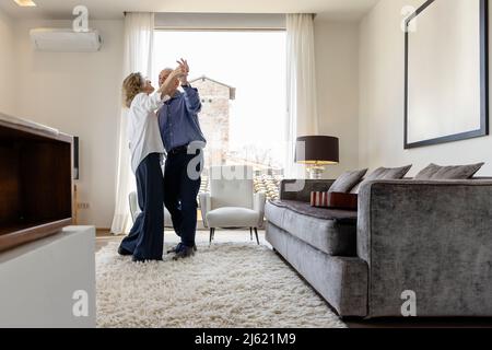 Senior couple dancing in living room at home Stock Photo