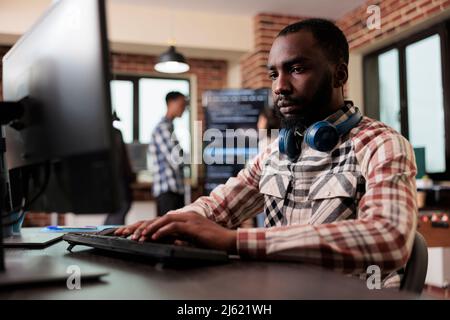 Advanced technology cyber developer creating a node network using binary encryption. African american programmer developing high security application with multiple layers of scalability. Stock Photo