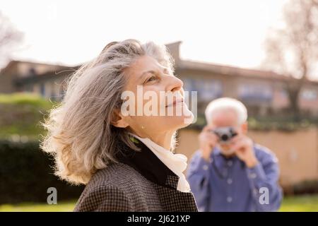 Senior man photographing woman on sunny day Stock Photo