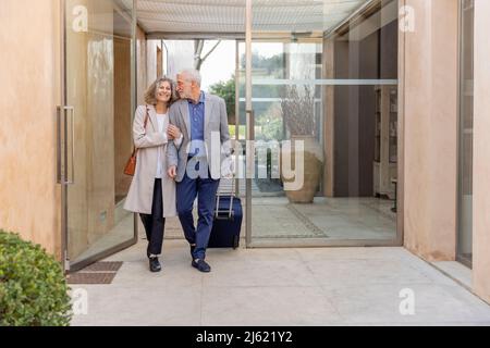 Smiling senior couple walking in lobby at boutique hotel Stock Photo
