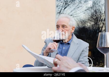 Senior man drinking wine sitting at table Stock Photo
