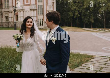 Smiling bride and groom holding hands walking on footpath Stock Photo