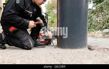 Construction worker with hammer working by metal pillar Stock Photo
