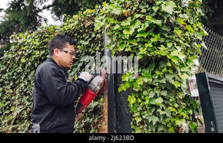 Man with grinder working on metal gate Stock Photo