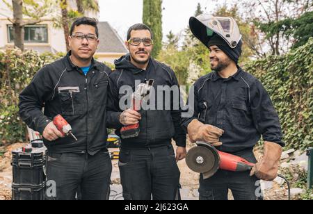 Happy workers with grinders and work tools at construction site Stock Photo