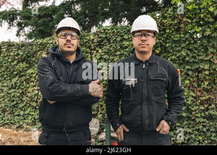Construction workers wearing hardhats standing at construction site Stock Photo