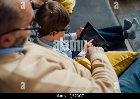 Boy e-learning through tablet PC by grandfather at home Stock Photo