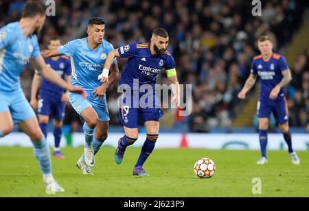 Manchester, England, 26th April 2022.  Karim Benzema of Real Madrid (C) is challenged by Rodri of Manchester City during the UEFA Champions League match at the Etihad Stadium, Manchester. Picture credit should read: Andrew Yates / Sportimage Credit: Sportimage/Alamy Live News Stock Photo