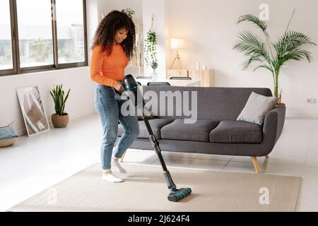 Young woman with vacuum cleaner doing housework at home Stock Photo