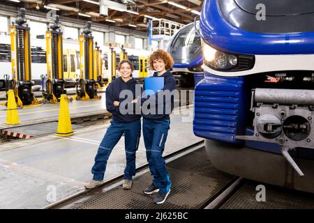 Smiling engineer holding file folder standing by colleague in factory Stock Photo