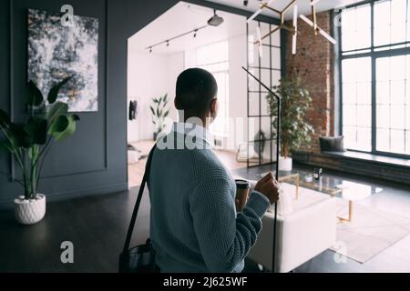 Young man holding disposable coffee cup arriving at home Stock Photo