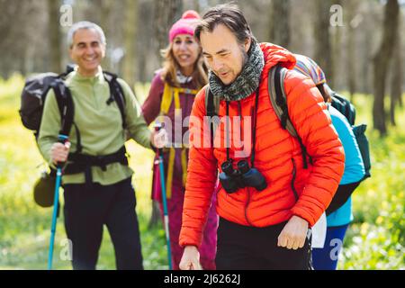 Man wearing binoculars trekking with friends in forest Stock Photo
