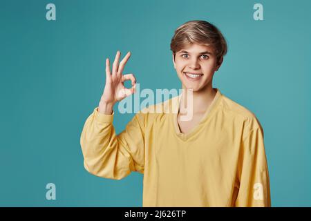 young smiling handsome guy showing Ok gesture Stock Photo