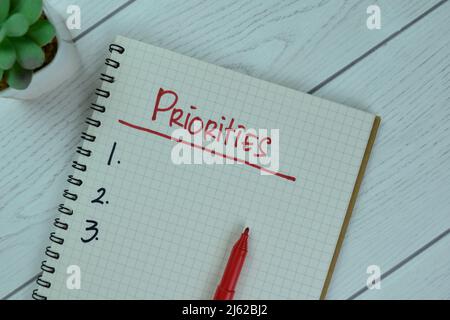 Set Priorities write on a book isolated on Wooden Table. Stock Photo