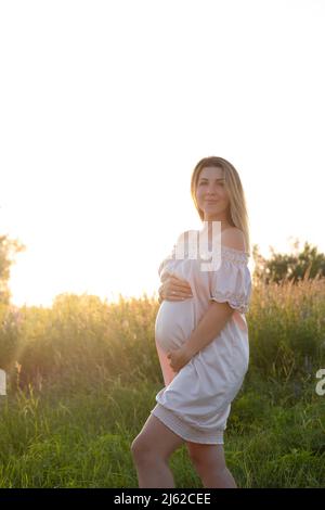 tender pregnancy portrait on sunset. expecting mother to be outside in pink dress. Beautiful tender mood photo of pregnancy Stock Photo