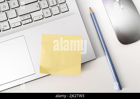 above view of blank yellow sticky note on laptop computer Stock Photo