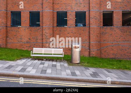 Hanley-Stoke-on-Trent, Staffordshire-United Kingdom April 21,2022 red brick multi storey car park behind a stainless steel litter bin and bench Stock Photo